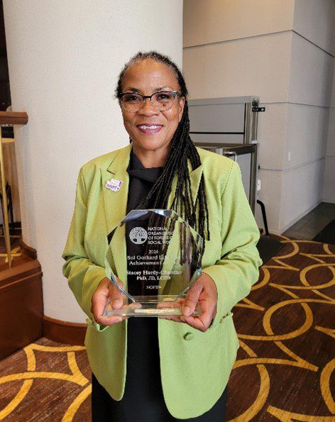 A woman holding an award in front of a wall.